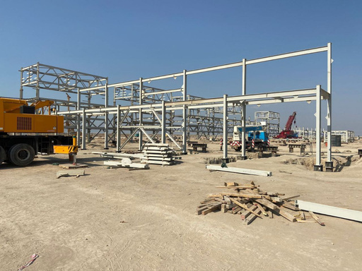 Unfinished steel structure frame with construction vehicles